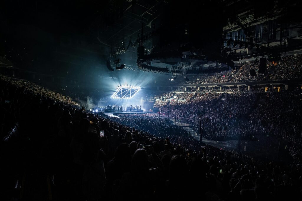 Energetic concert scene featuring a packed audience, vibrant lights, and a live performance on stage.