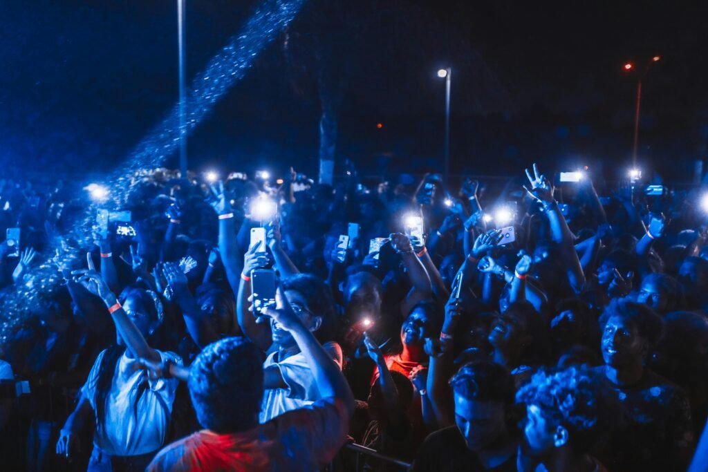 Vibrant nighttime concert crowd with illuminated phones and energetic atmosphere.