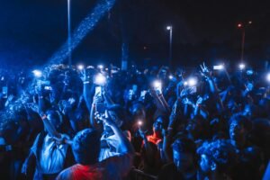 Vibrant nighttime concert crowd with illuminated phones and energetic atmosphere.